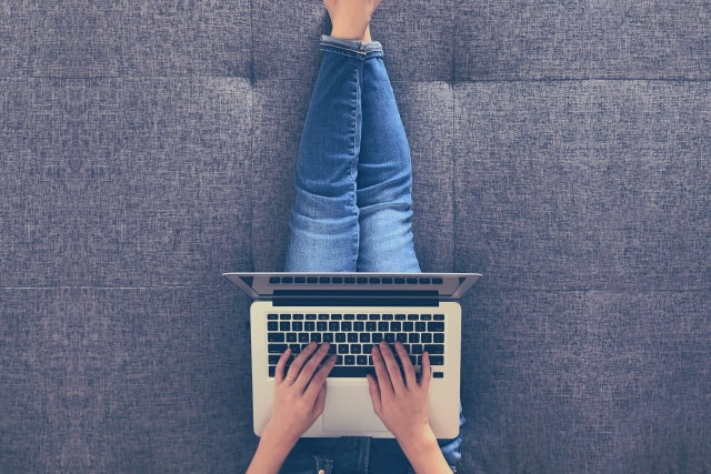 膝の上でパソコンを使っている女性